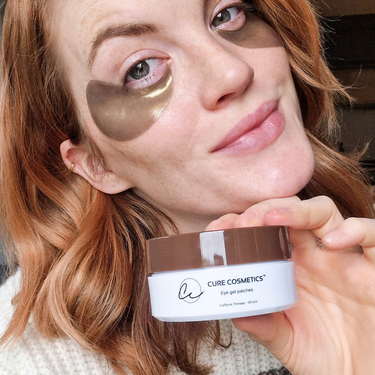 Kvinne med Caffeine Therapy øyemasker fra Cure Cosmetics som reduserer mørke ringer og gir huden under øynene frisk glød.