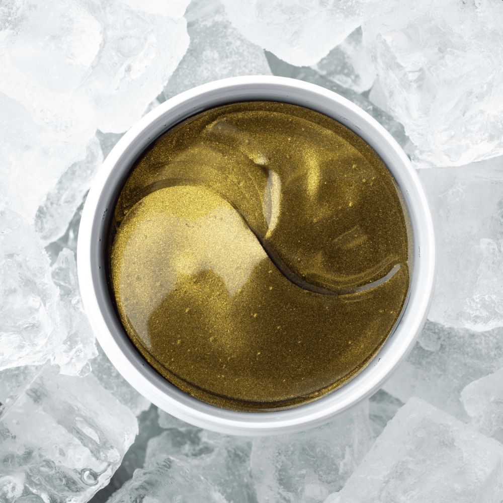 Caffeine Therapy hydrogel-øyemasker fra Cure Cosmetics plassert på is for å illustrere den oppfriskende effekten mot mørke ringer og trøtt hud.