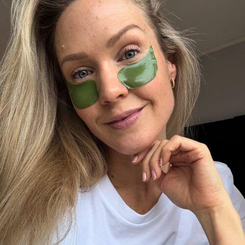 Kvinne med Seaweed Therapy øyemasker fra Cure Cosmetics som reduserer poser under øynene og gir naturlig glød.